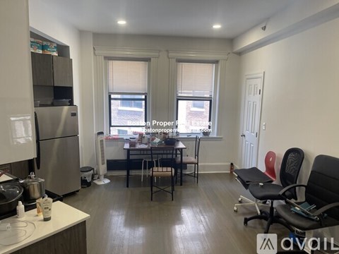 A kitchen with a refrigerator, a table with chairs, and a window.
