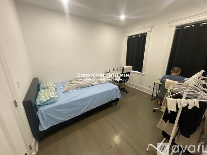 A bedroom with a bed, a chair, and a clothes drying rack.