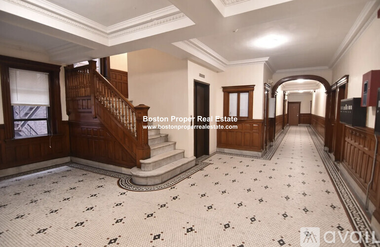 A spacious hallway with a staircase and a tiled floor.