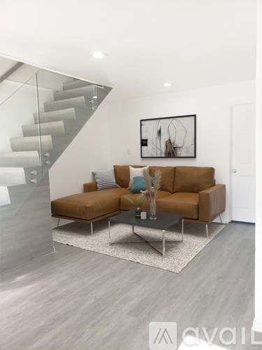 A living room with a brown couch and a glass staircase.