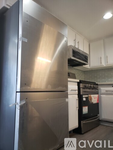 A kitchen with a stainless steel refrigerator and white cabinets.