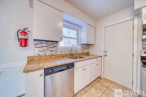 A kitchen with a granite countertop and a red fire extinguisher mounted on the wall.