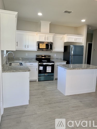 A kitchen with white cabinets and a granite countertop.
