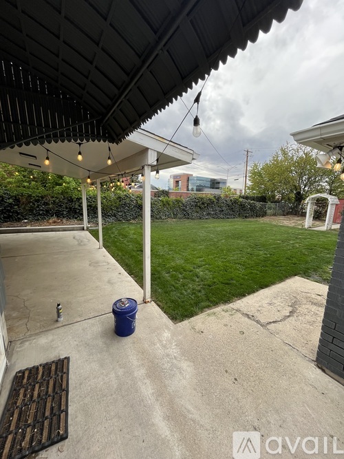A patio with a blue bucket and a white pole.