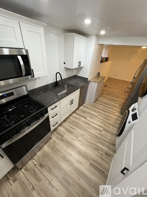 A kitchen with white cabinets and a black countertop.