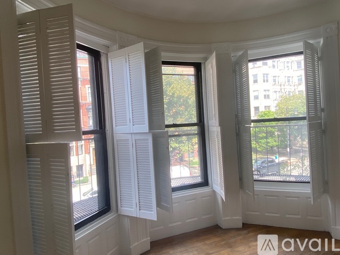 A room with three windows covered by white shutters.