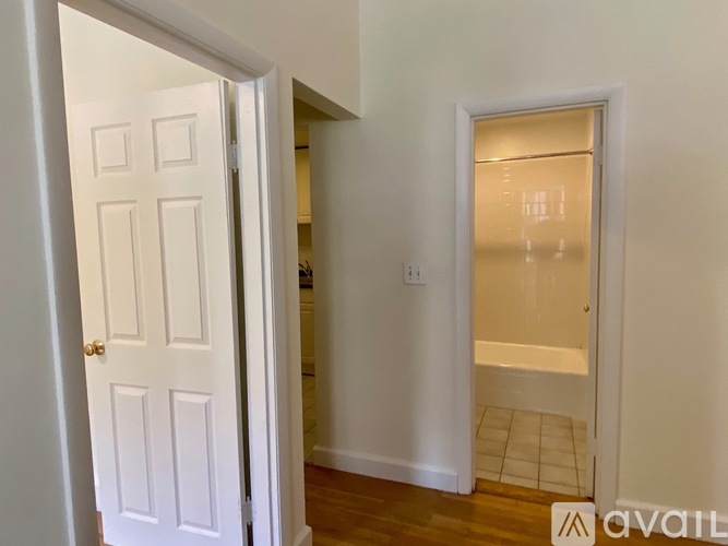 A white door is open to a hallway with a tiled floor.