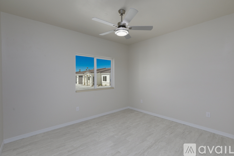 A room with a ceiling fan and a window showing a view of a building.