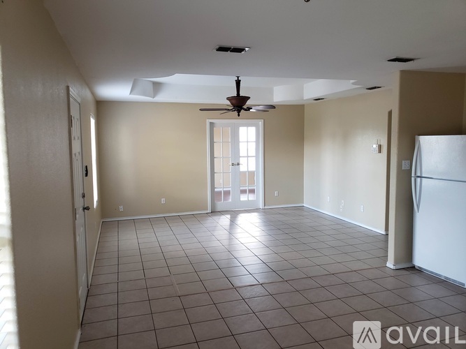 A spacious room with tile flooring and a ceiling fan.