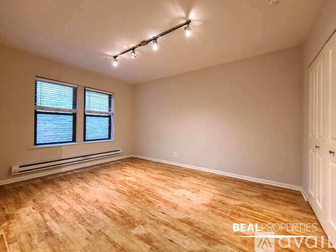 A room with wooden flooring and a window with blinds.
