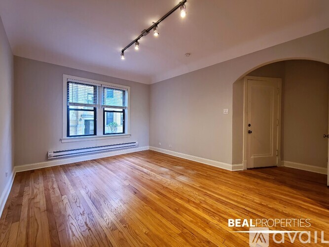 A room with wooden floors and a window with blinds.