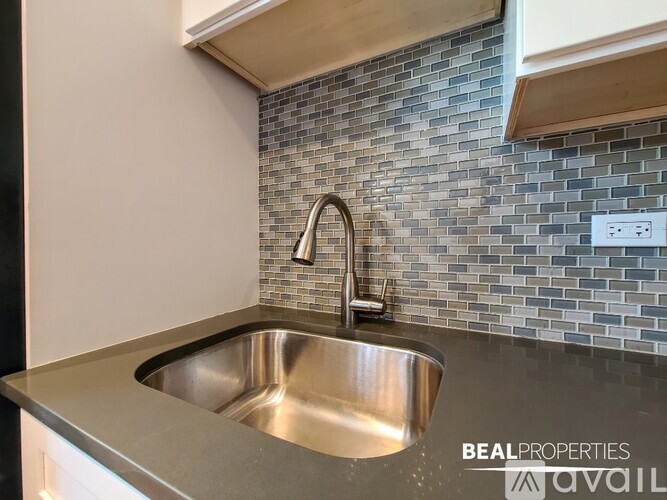 A modern kitchen with a stainless steel sink and a tile backsplash.