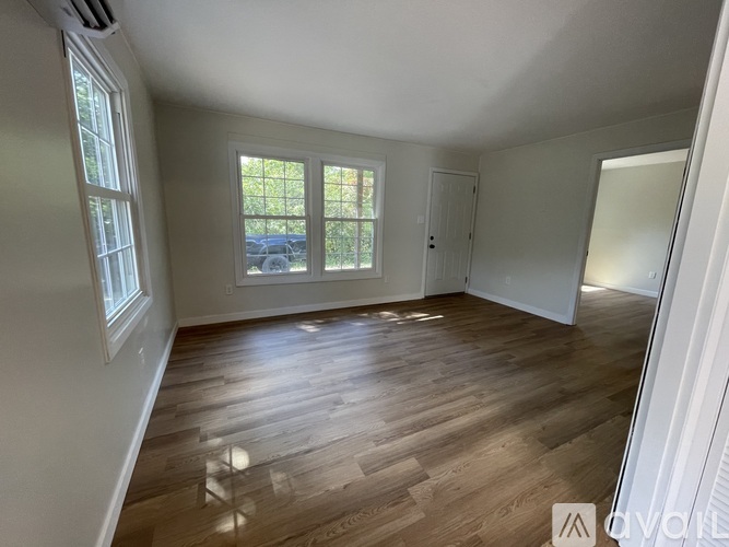 A room with wooden flooring and a window overlooking a parking lot.