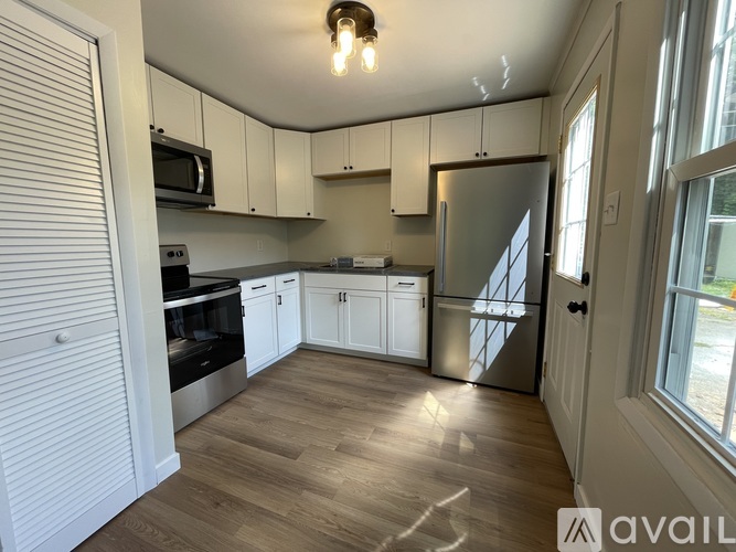 A kitchen with white cabinets and a wooden floor.