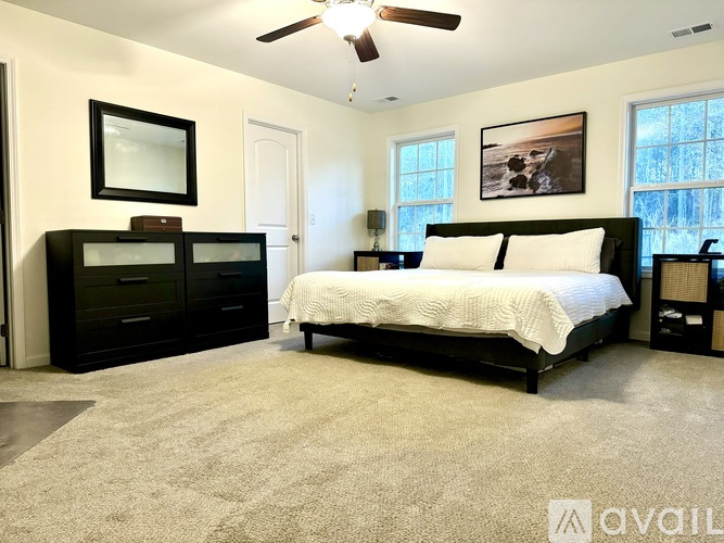 A bedroom with a bed, dresser, and ceiling fan.
