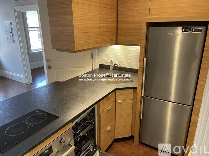 A kitchen with wooden cabinets and a stainless steel refrigerator.