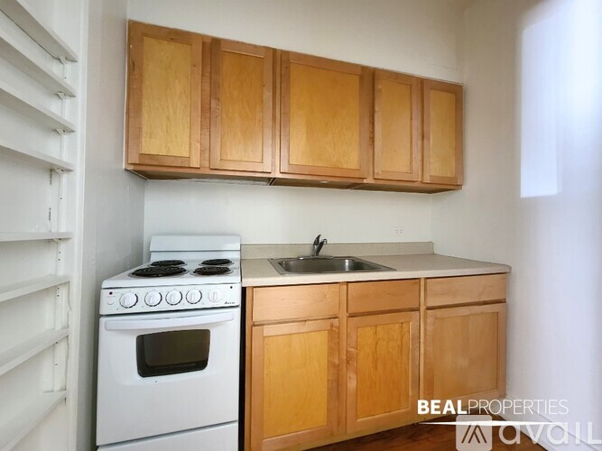 A kitchen with wooden cabinets and a white stove top oven.