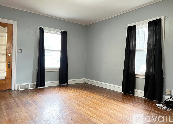 A room with black curtains and wooden flooring.
