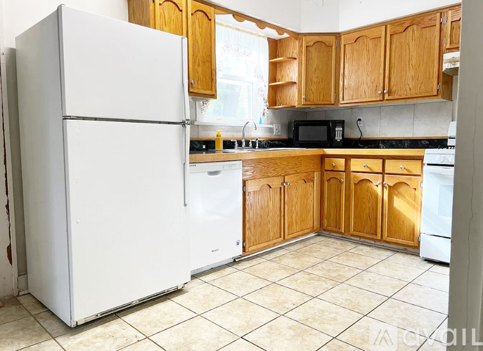 A white refrigerator is in a kitchen with wooden cabinets.