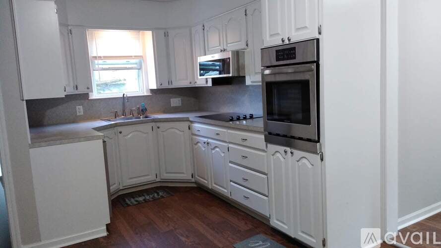 A kitchen with white cabinets and a wooden floor.