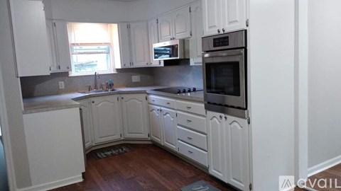 A kitchen with white cabinets and a wooden floor.