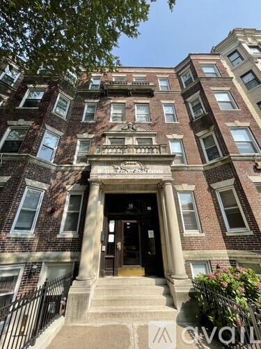 The front of a brick building with a black door and steps leading up to it.