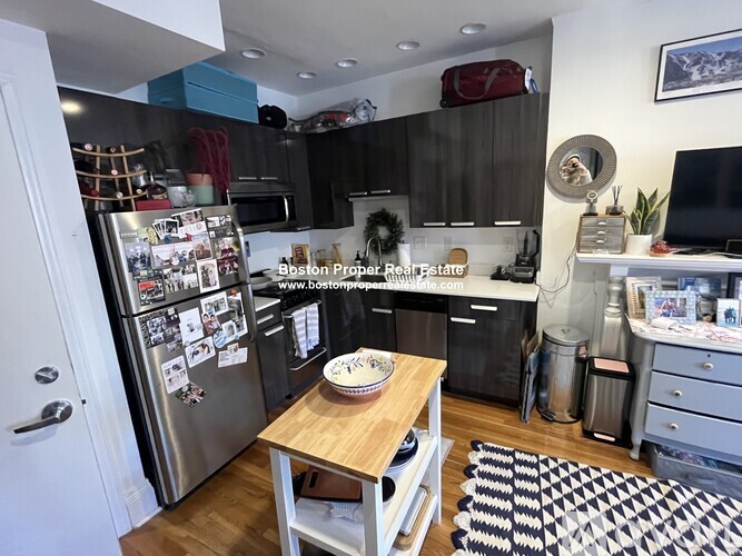 A kitchen with a fridge full of magnets and a table with a pie on it.