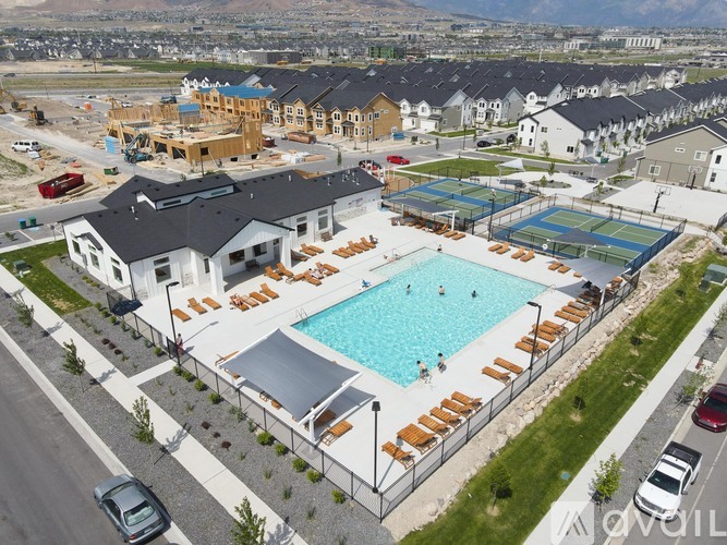 A large swimming pool surrounded by sun loungers and apartment buildings.