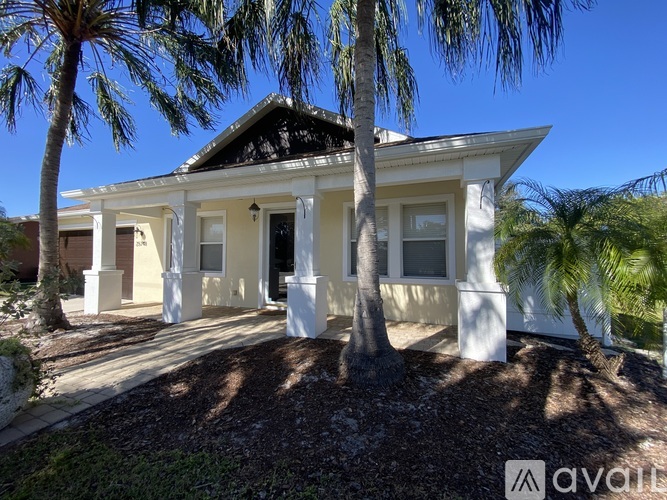 A white house with a black roof and a palm tree in front.