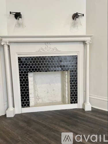 A fireplace with a white mantle and a black and white tile surround.