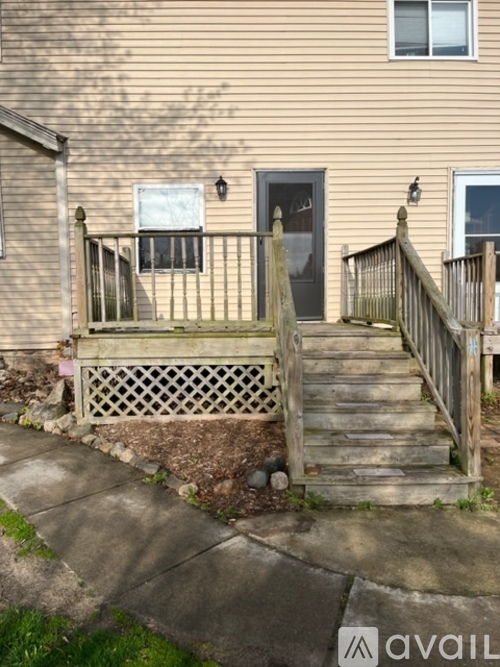 A house with a brown door and a wooden staircase leading to it.