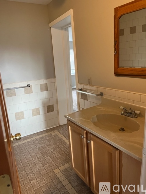 A bathroom with a sink, mirror, and tiled floor.
