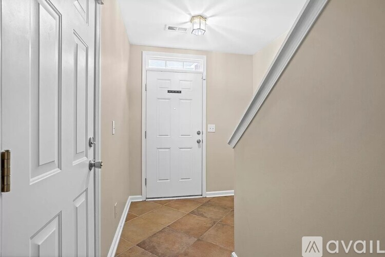 A hallway with a white door and a tiled floor.