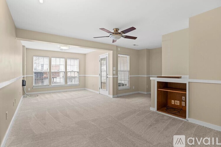 A spacious room with a ceiling fan and carpeted floor.
