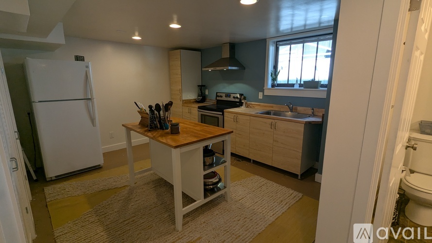 A kitchen with a white refrigerator and wooden island.