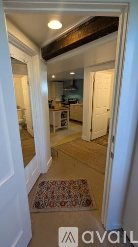 A hallway with a rug on the floor and a door on the right.