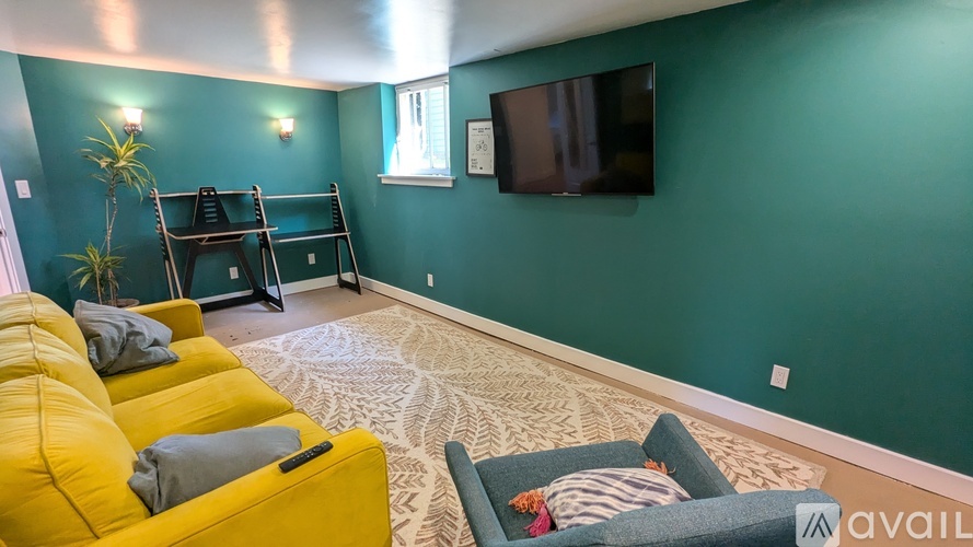 A living room with a yellow couch and a television on the wall.