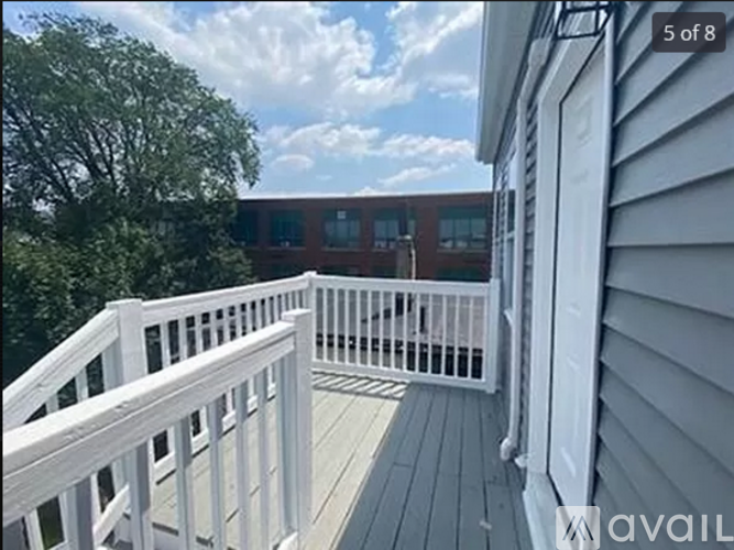 A white deck with a railing and a building in the background.