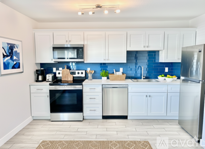 A kitchen with white cabinets and a blue backsplash.