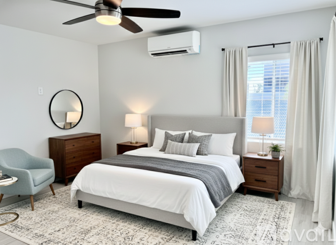 A bedroom with a large bed, a chair, and a ceiling fan.