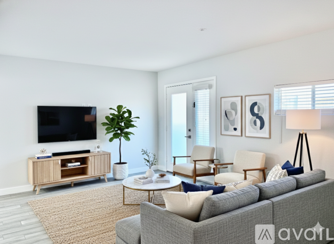 A living room with a grey couch, a television, a plant, and a coffee table.