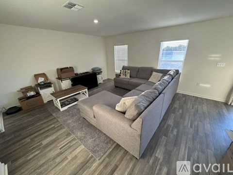 A living room with a grey couch and wooden flooring.