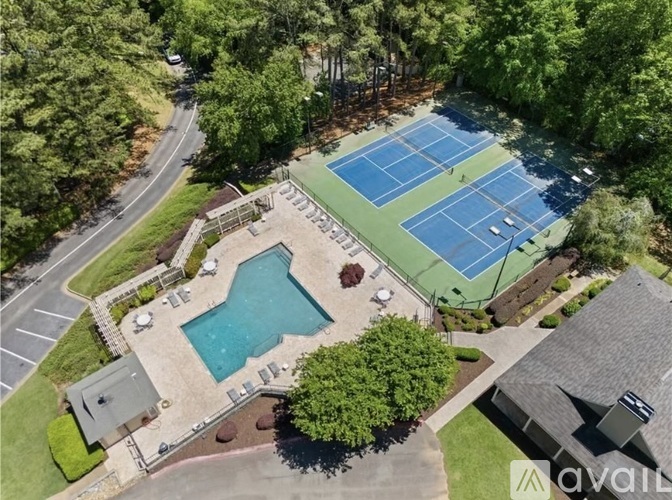 An aerial view of a tennis court, a pool, and a small building.