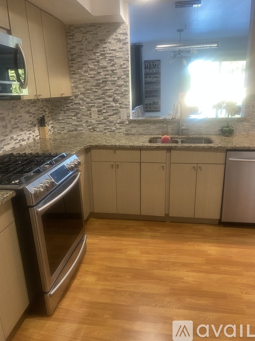 A kitchen with a stone backsplash and wooden floors.