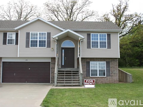 A house with a garage and a sign that says "For Rent".