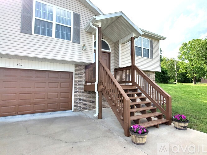 A house with a brown garage door and a wooden staircase leading to the entrance.