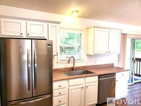 A kitchen with a stainless steel refrigerator and white cabinets.