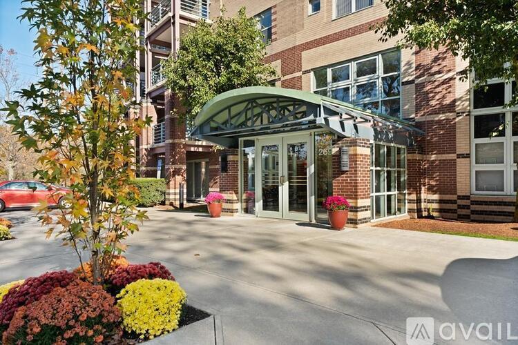 A building entrance with a green awning and a tree with red leaves.