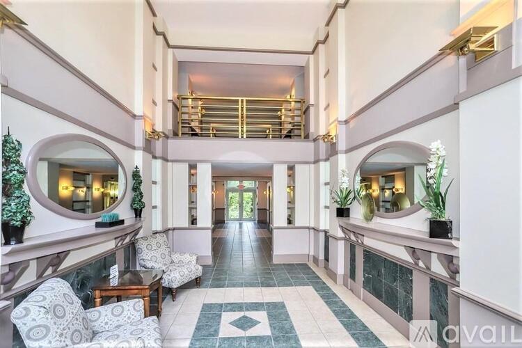 A spacious hallway with a bench, chairs, and a decorative floor.