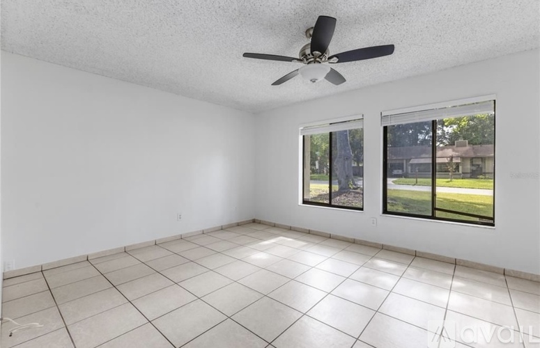 A spacious room with a ceiling fan and large windows.